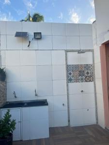 una cocina con paredes de azulejos blancos y fregadero en Casa em Condomínio, Piscina Privativa e Área Gourmet, en Camaçari