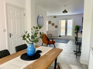 uma sala de jantar com um vaso azul sobre uma mesa de madeira em The Town House, whole house suitable for contractors and families em Market Harborough