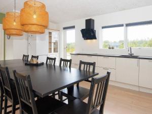 14 person holiday home in Glesborg في Glesborg: مطبخ وغرفة طعام مع طاولة سوداء وكراسي