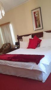 a bedroom with a large bed with red and white pillows at Tshulu Tsha Nabe B&B in Bulawayo