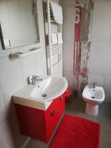a bathroom with a red sink and a toilet at B&B Antico Porto Tarquinia in Tarquinia