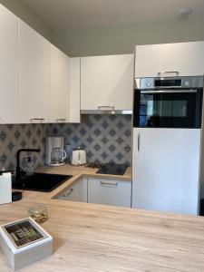 uma cozinha com armários brancos e um frigorífico branco em Marianne 1 em Bergerac