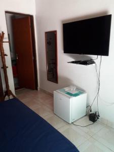um quarto com uma cama e uma televisão de ecrã plano em Casa de Temporada no Paraíso Guaraú em Peruíbe