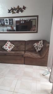 a brown leather couch in a living room with a mirror at Casa de Temporada no Paraíso Guaraú in Peruíbe