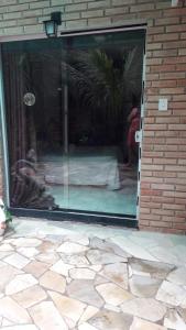 uma porta de vidro de uma casa com uma cama em Casa de Temporada no Paraíso Guaraú em Peruíbe