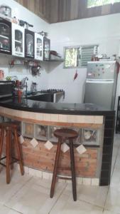a kitchen with a counter with two stools in it at Casa de Temporada no Paraíso Guaraú in Peruíbe