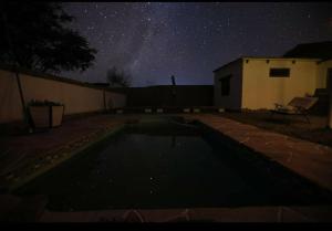 a starry night with a swimming pool in a yard at Cabañas Voyage Atacama in San Pedro de Atacama
