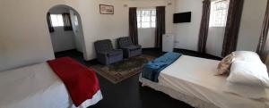 een slaapkamer met 2 bedden en een stoel. bij Tshulu Tsha Nabe B&B in Bulawayo
