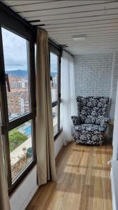 - un salon avec une chaise et de grandes fenêtres dans l'établissement Apartamento playa San Lorenzo, à Gijón