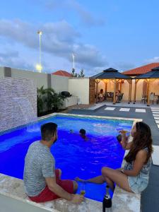 a man and woman sitting next to a swimming pool at Dushi Experience in Paradera