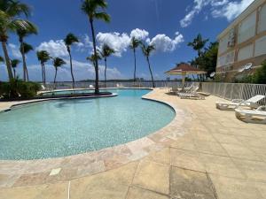 a swimming pool with palm trees and a building at Flamboyant Oasis in Baie Nettle