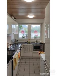 a kitchen with white cabinets and a sink and two windows at THE BEST LAKE HOUSE -3 minutes to the train in Spiez