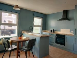 a kitchen with blue walls and a table and chairs at Cathedral Quarter Apartments in Derry Londonderry