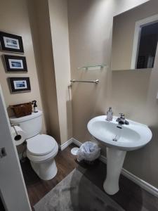 a white bathroom with a toilet and a sink at Your Oasis in Niagara Falls Canada in Niagara Falls