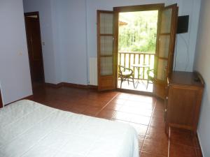 a bedroom with a bed and a balcony with a table at Hotel Apartamentos La Hortona in Soto de Luiña
