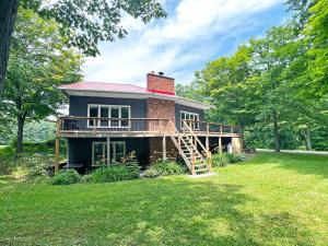 a large house with a deck on a lawn at Forest Retreat - Pool - Games - Fireside Joy in Cayuga