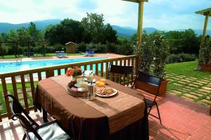 einen Tisch mit Essen auf einer Terrasse neben einem Pool in der Unterkunft Agriturismo La Burraia in Gambassi Terme