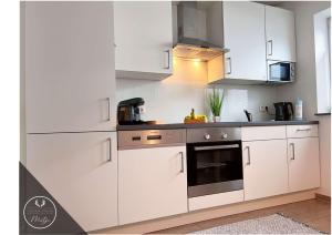 a kitchen with white cabinets and an oven at Ferienwohnung MOTJE in Rastede in Rastede