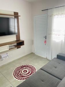 ein Wohnzimmer mit einem TV und einem Teppich auf dem Boden in der Unterkunft Casa completa e espaçosa in Foz do Iguaçu