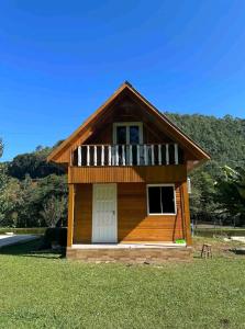 a small house with a balcony on the grass at Sítio Recanto Nativo in Palmitos