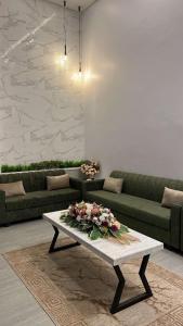 a living room with a couch and a table with flowers on it at غرف قاعة وشاليه ومسبح ماز in Al Rass