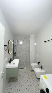 La salle de bains est pourvue de 2 lavabos et de 2 toilettes. dans l'établissement Urban Serenity Skyline View Apartment 2, à Tirana