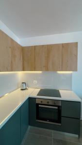 a kitchen with wooden cabinets and a stove top oven at Urban Serenity Skyline View Apartment 2 in Tirana