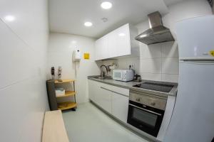 cocina pequeña con armarios blancos y fogones en Scout Madrid Hostel, en Madrid