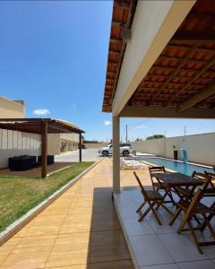 eine Terrasse mit Stühlen, einem Tisch und einem Auto in der Unterkunft DUNAS RESIDENCE CASA 02 in Santo Amaro