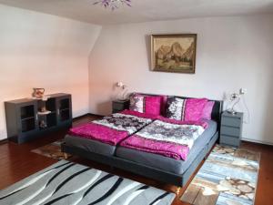 een slaapkamer met een zwart bed met roze kussens bij Ferienhäuschen Berg und Tal in Harzgerode