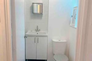 a white bathroom with a toilet and a sink at Cosy flat in the Heart of Wandsworth in London