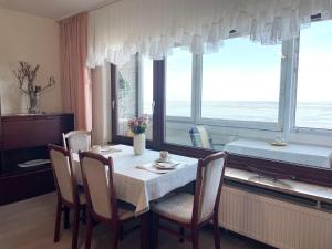 uma sala de jantar com mesa, cadeiras e janelas em Strandhochhaus-Whg-J12 em Cuxhaven