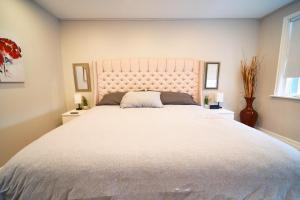 a bedroom with a large white bed with two windows at Hamilton Mountain Plaza - King Bed - Main Floor in Hamilton