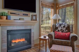 ein Wohnzimmer mit einem Kamin, einem Stuhl und einem TV in der Unterkunft Boyne Mountain Disciples Village Unit 660 in Boyne Falls