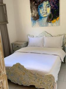 a bedroom with a white bed with a painting on the wall at cristal appart in Essaouira