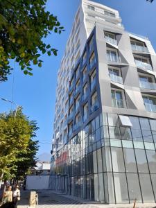 a tall building with glass windows on a street at Urban Serenity Skyline View Apartment 2 in Tirana