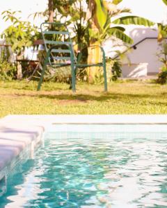 a swimming pool with a chair next to it at Vila Vale Guest House - Surf & Yoga in Charneca