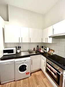 een keuken met een wasmachine en een wastafel bij Maida Vale Serenity: 2-Bedroom in Londen