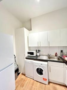 een keuken met een wasmachine en een wastafel bij Maida Vale Serenity: 2-Bedroom in Londen