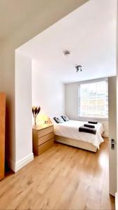 een witte slaapkamer met een bed en een raam bij Maida Vale Serenity: 2-Bedroom in Londen