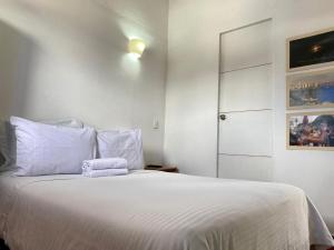 a bedroom with a bed with white sheets and a door at Zana Hotel Boutique in Bogotá