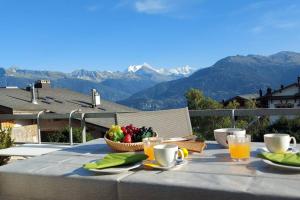 einen Tisch mit einer Schale Obst und einem Korb mit Obst, gmaxwell gmaxwellzos in der Unterkunft Charmant logement vue dégagée in Crans-Montana