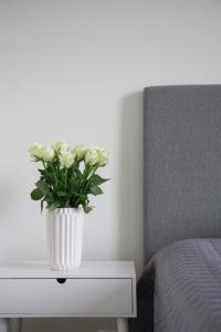 a white vase with flowers on a table next to a bed at Lovely 2R apartment in Oulu