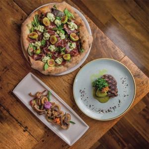 a pizza and two plates of food on a wooden table at Best Western Hotel Santa Caterina in Acireale +143 photos