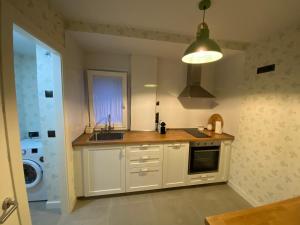 a kitchen with white cabinets and a sink and a washer at Piso acogedor entre mar y montaña in Posada de Llanes