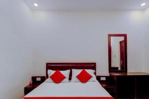een slaapkamer met een bed met rode kussens en een spiegel bij Flagship Hotel Days Inn in Rānchī