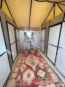 an inside view of a tent with a rug on the floor at Sahara Ousis Camp in Merzouga
