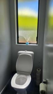 a bathroom with a white toilet with a window at Beach House Matauri Bay in Matauri Bay