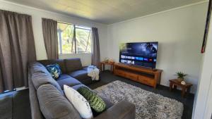 a living room with a couch and a flat screen tv at Beach House Matauri Bay in Matauri Bay