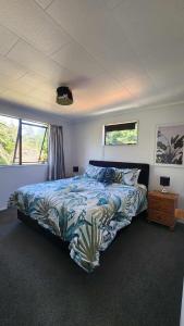 a bedroom with a bed and two windows at Beach House Matauri Bay in Matauri Bay